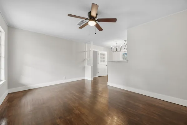 a view of empty room with wooden floor and ceiling fan
