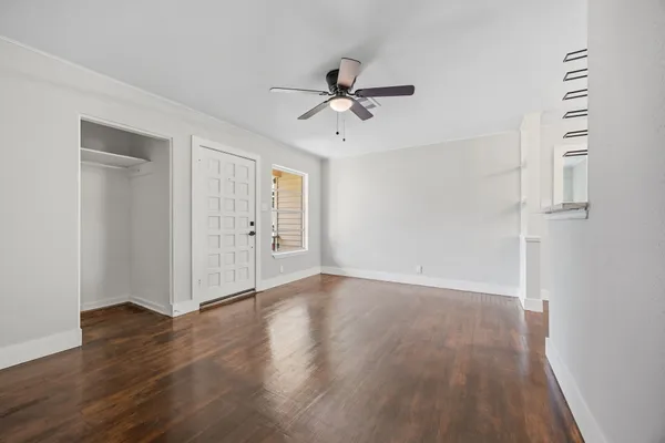 an empty room with wooden floor fan and windows
