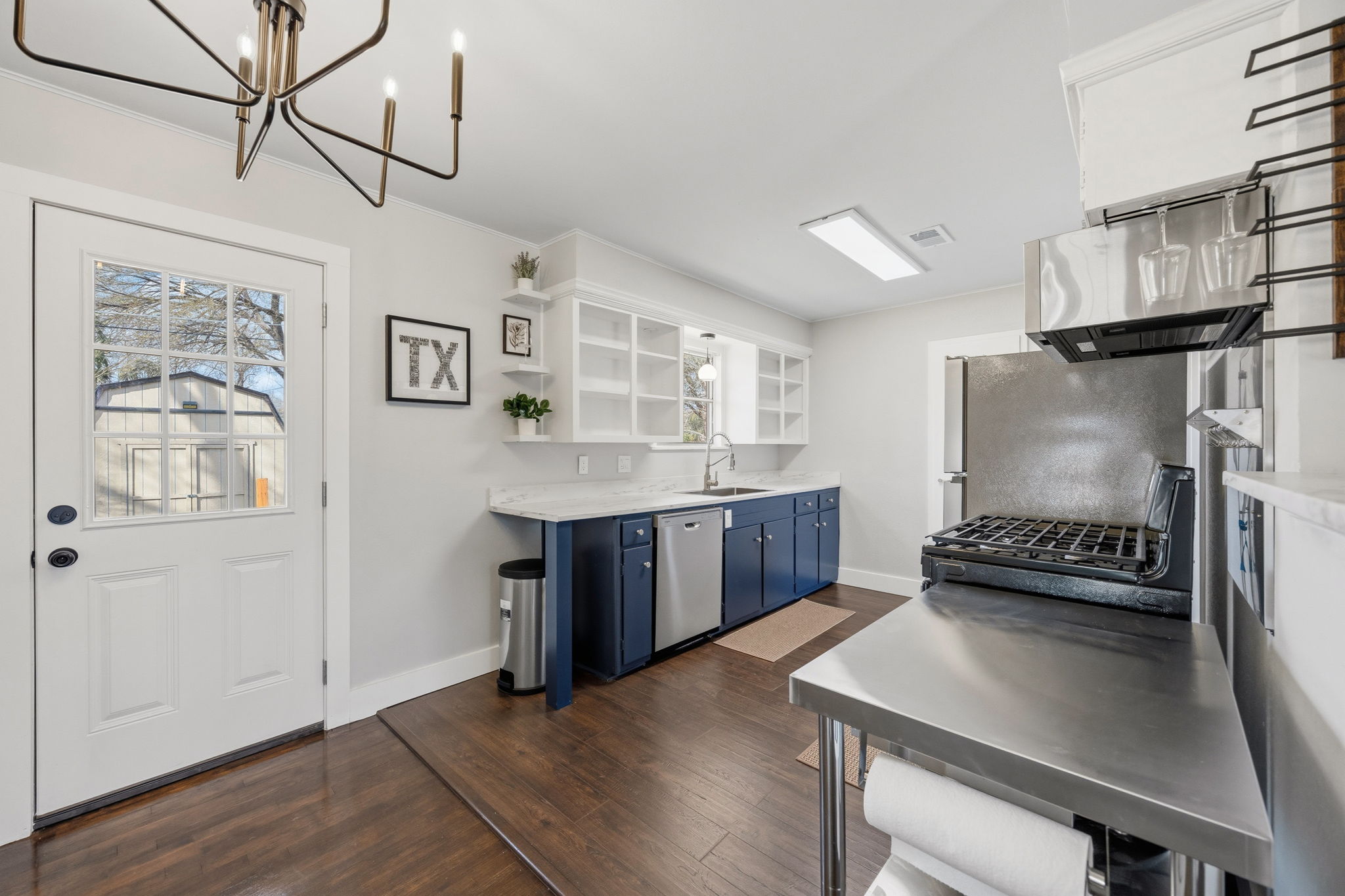 1402 Kent Street Taylor, TX 76574 - Photo 7 of 25 a kitchen with stainless steel appliances granite countertop a stove a refrigerator and a dining table with wooden floor