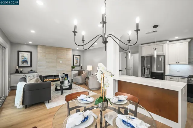 a living room with furniture kitchen view and a chandelier