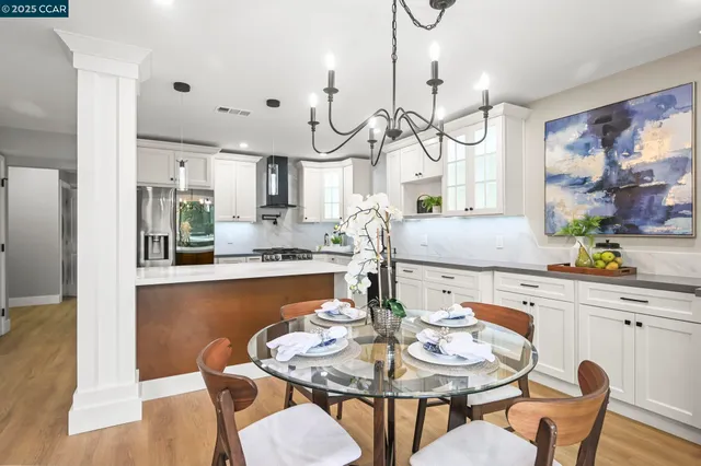 a kitchen with stainless steel appliances granite countertop a dining table chairs and a chandelier