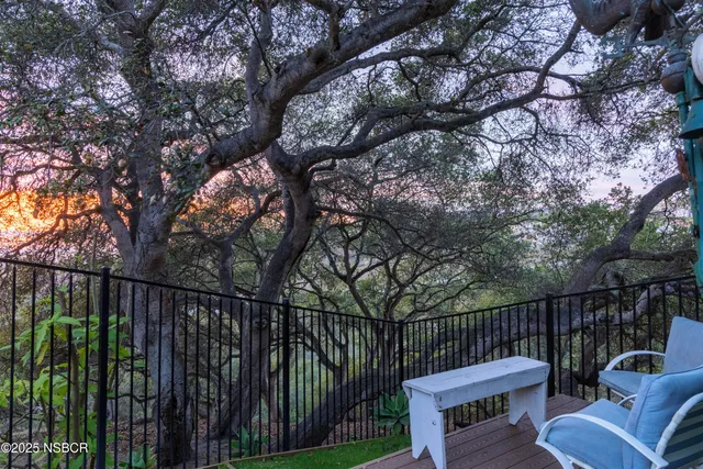 a view of a roof deck with couches and wooden fence