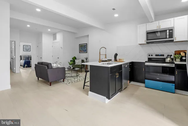 a kitchen with kitchen island stainless steel appliances a sink a counter top space cabinets and a couch