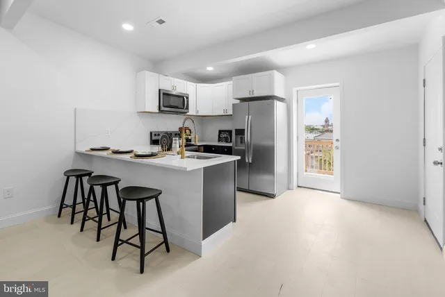 a kitchen with stainless steel appliances a refrigerator a stove a sink a dining table and chairs