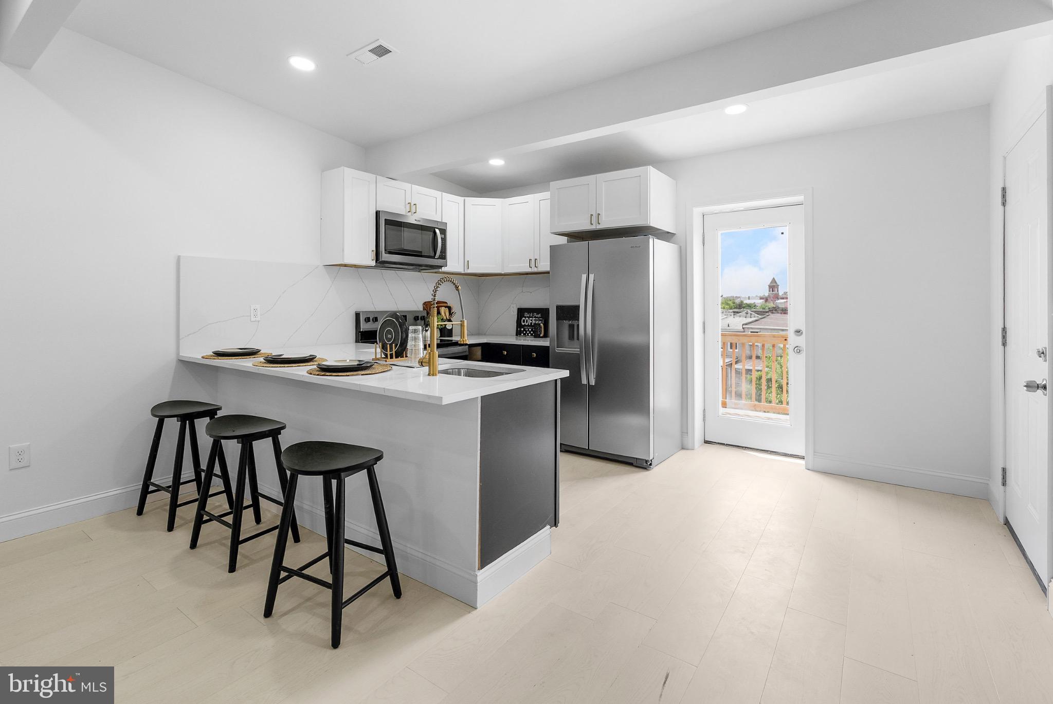 2106 McCulloh Street Baltimore, MD 21217 - Photo 19 of 38 a kitchen with stainless steel appliances a refrigerator a stove a sink a dining table and chairs