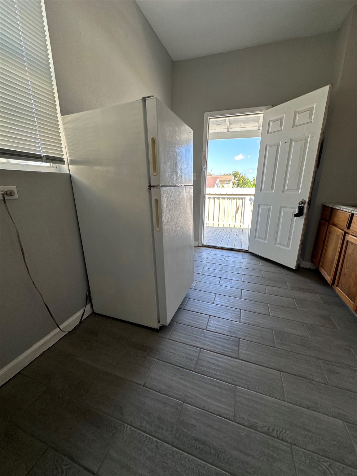 910 37th Street, Unit 3 Galveston, TX 77550 - Photo 7 of 18 a view of a refrigerator in kitchen and an empty room with wooden floor