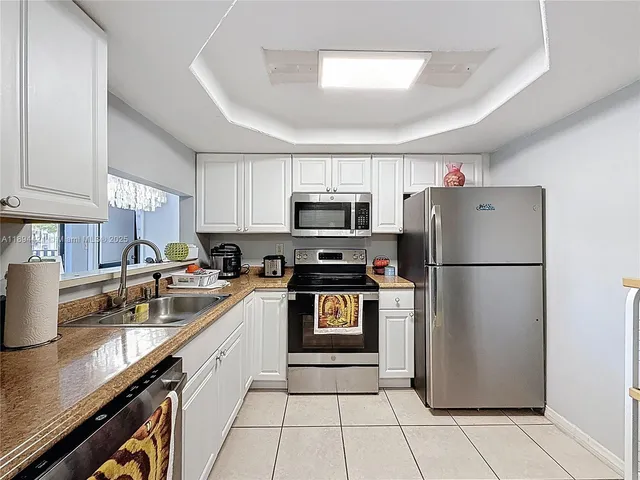 a kitchen with a refrigerator a microwave a sink and cabinets