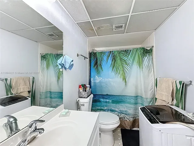 a bathroom with a sink a toilet a mirror and shower curtain