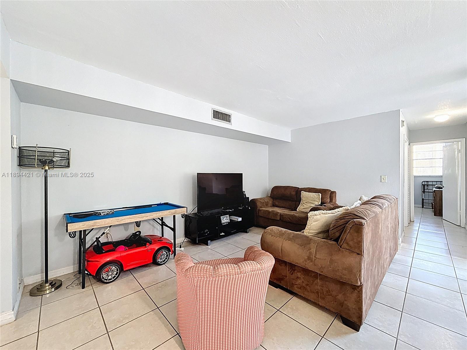 3611 Southwest 117th Avenue, Unit 10207 Miami, FL 33175 - Photo 10 of 35 a living room with furniture a flat screen tv and a table