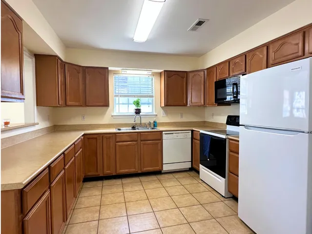 a kitchen with a refrigerator sink and wooden cabinets