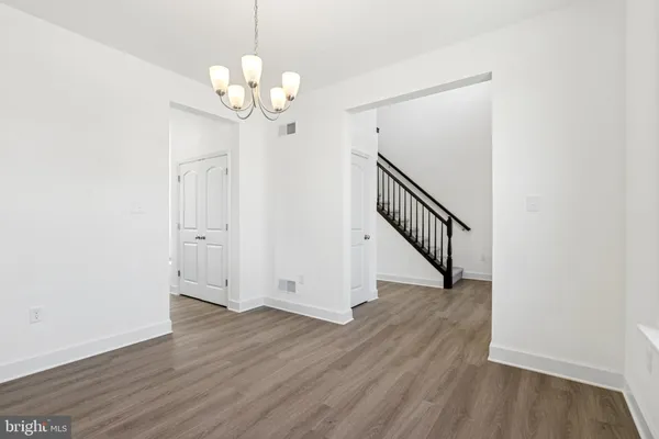 a view of a hallway with wooden floor and chandelier