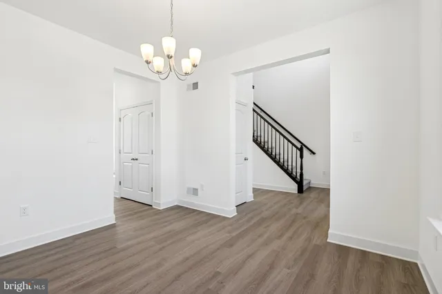 a view of a hallway with wooden floor and chandelier