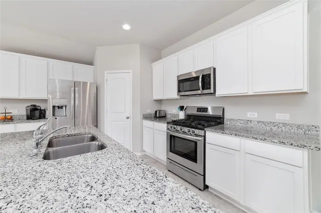 a kitchen with granite countertop a sink stove and refrigerator