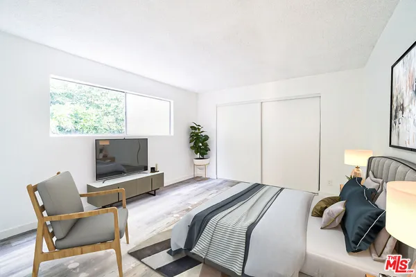 a bedroom with a bed chair and flat screen tv
