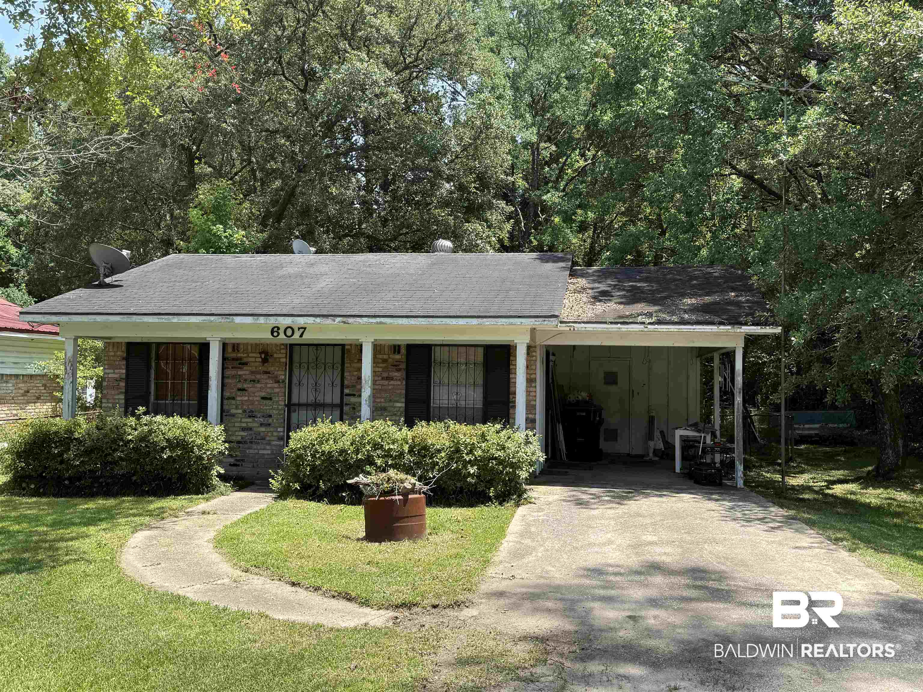 607 West Lee Street Mobile, AL 36611 - Photo 1 of 11 View of front of house with driveway, a carport, a front lawn, a shingled roof, and brick siding
