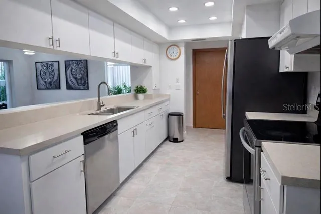 a kitchen with kitchen island granite countertop a sink stainless steel appliances and cabinets