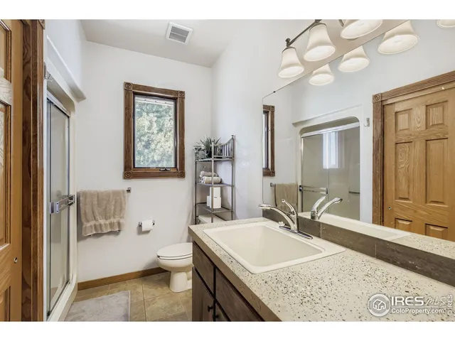 a bathroom with a granite countertop sink a toilet a mirror and shower