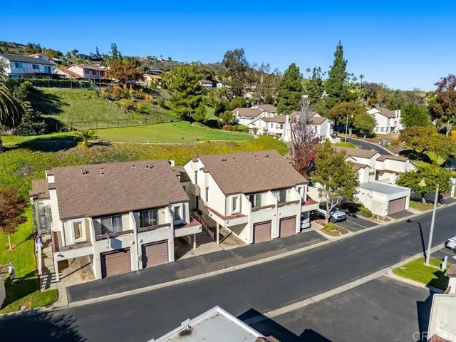 an aerial view of residential houses with outdoor space and ocean view