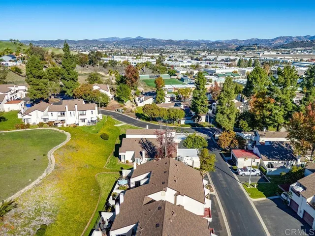 an aerial view of a city with lots of residential buildings ocean and mountain view in back