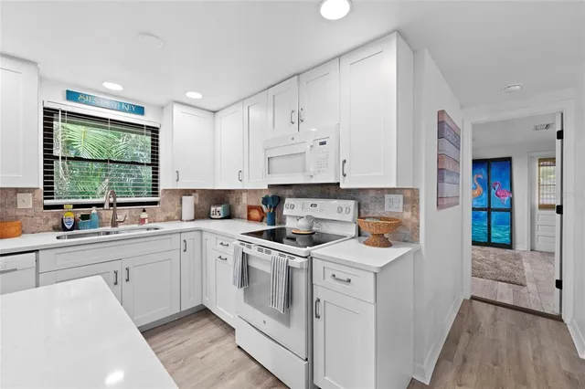 a kitchen with sink a refrigerator and chairs