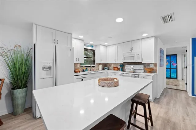 a kitchen with stainless steel appliances granite countertop a dining table chairs refrigerator sink and cabinets