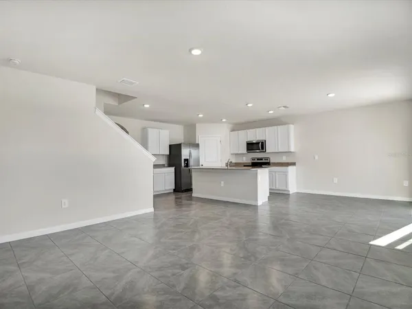 a view of kitchen with kitchen island granite countertop a stove a sink and a refrigerator