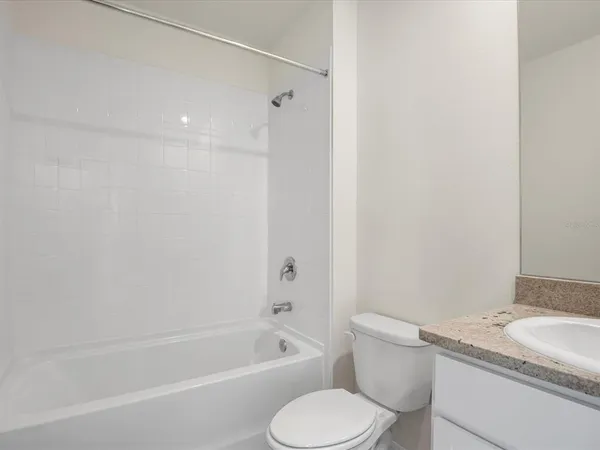 a bathroom with a granite countertop toilet a sink and bathtub
