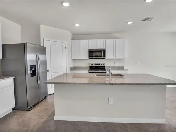a kitchen with stainless steel appliances granite countertop a refrigerator a stove a sink and a granite counter tops