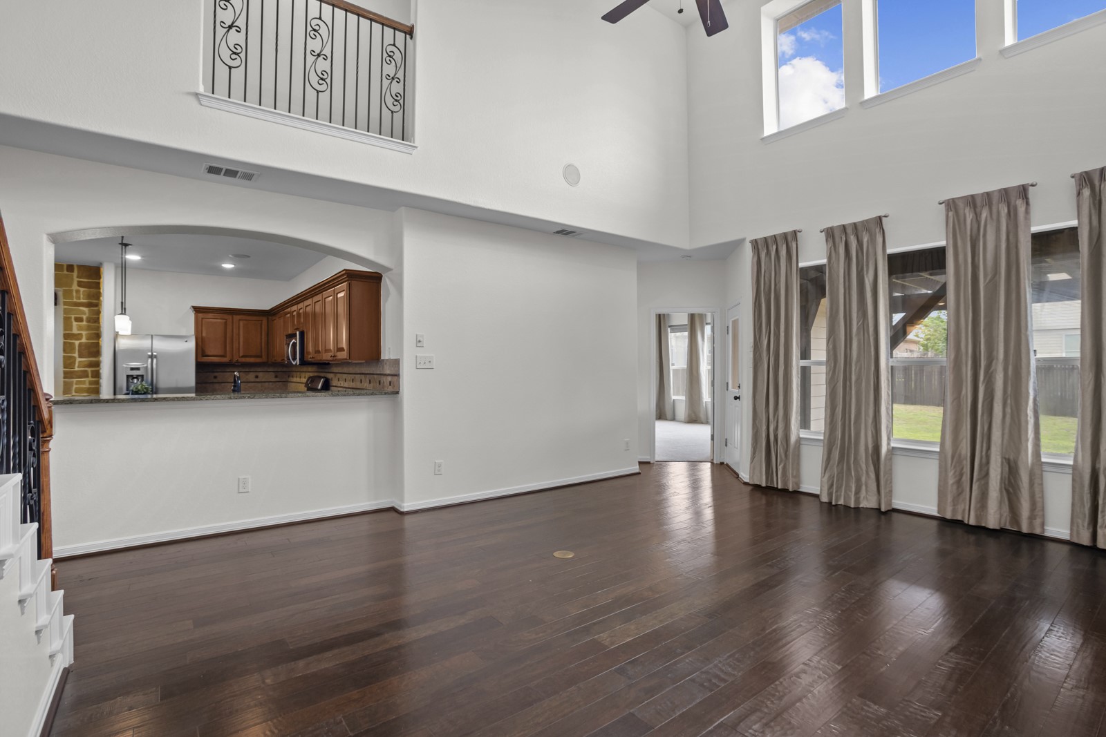 245 Razzmatazz Trail Buda, TX 78610 - Photo 16 of 37 Two-story living area with dark wood-finish flooring, high ceilings, and abundant natural light from upper and lower windows