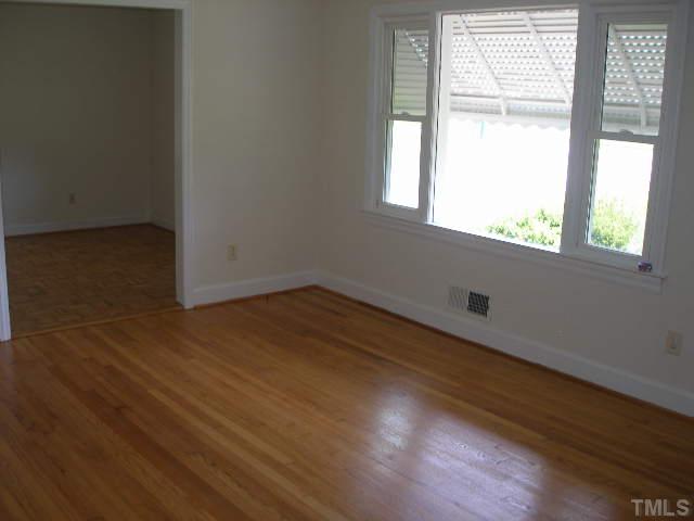 1218 Southerlund Road Garner, NC 27529 - Photo 3 of 10 an empty room with wooden floor and windows