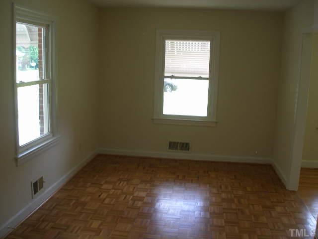 1218 Southerlund Road Garner, NC 27529 - Photo 5 of 10 an empty room with wooden floor and windows