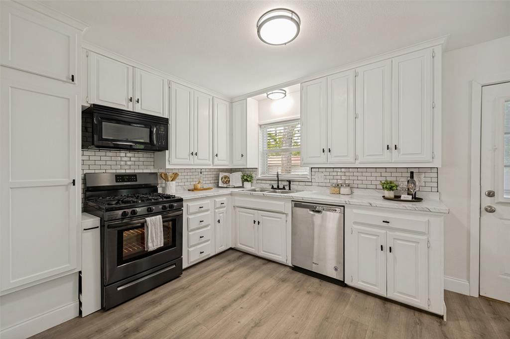 2316 Cunningham Street Irving, TX 75062 - Photo 7 of 22 White kitchen cabinetry with black hardware, subway tile backsplash, light wood-finish flooring, and recessed lighting