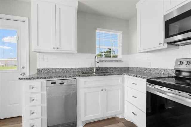 a kitchen with granite countertop white cabinets and appliances