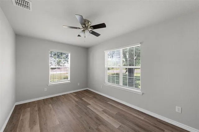 a view of an empty room with a window and wooden floor