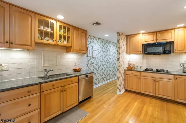 a kitchen with stainless steel appliances granite countertop a sink a stove a microwave a refrigerator and cabinets