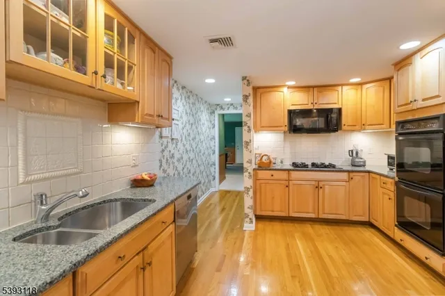 a kitchen with stainless steel appliances granite countertop a sink a stove and a wooden cabinets