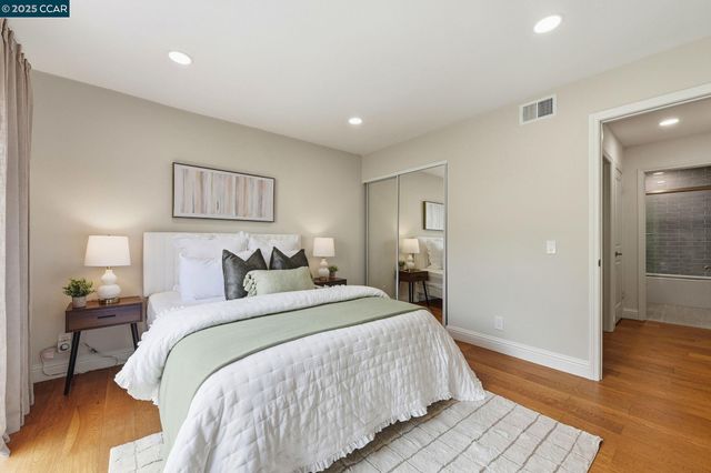 a spacious bedroom with a bed and wooden floor