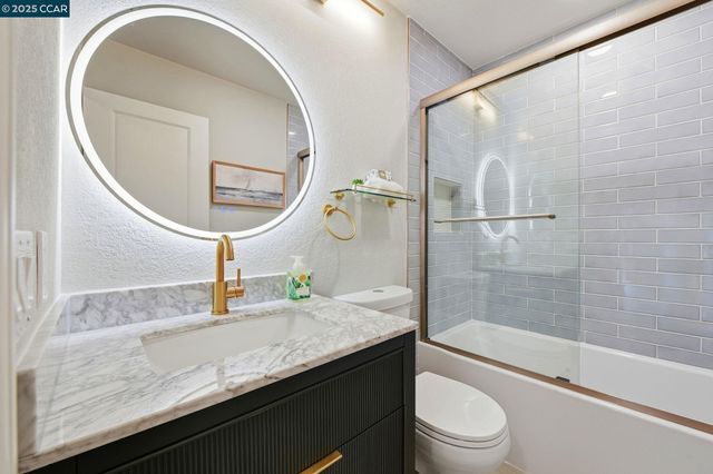 a bathroom with a granite countertop sink a toilet and shower
