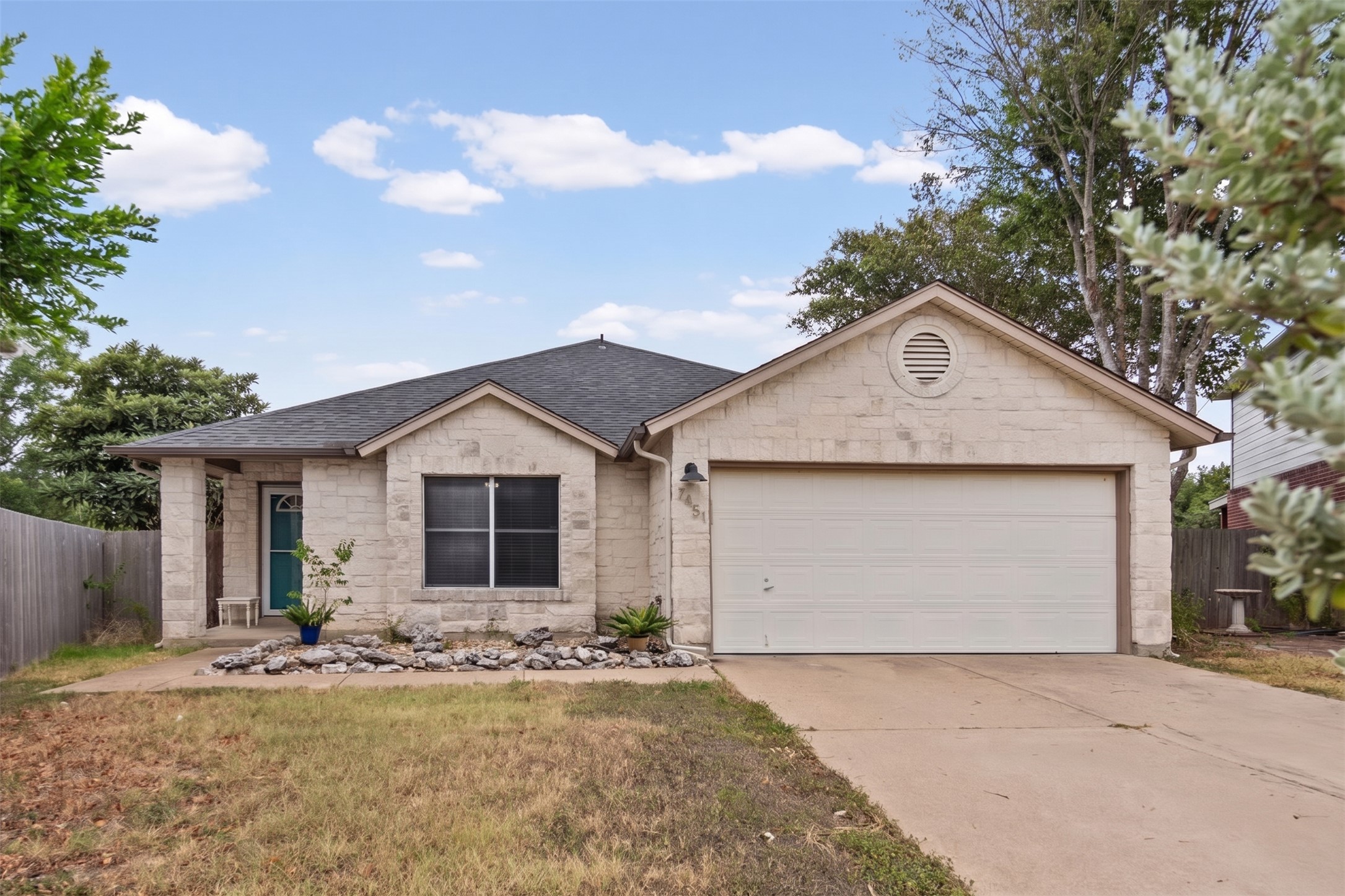 All sides stone exterior, shingle roof, and concrete driveway define this single-story suburban home.