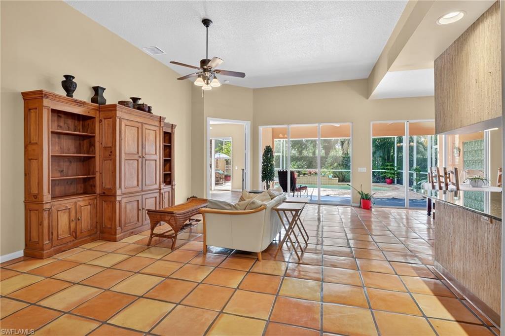 5902 Bermuda Lane Naples, FL 34119 - Photo 6 of 50 a living room with furniture a flat screen tv and a floor to ceiling window