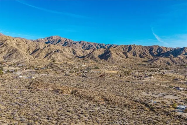 a view of a dry yard with mountains in the background