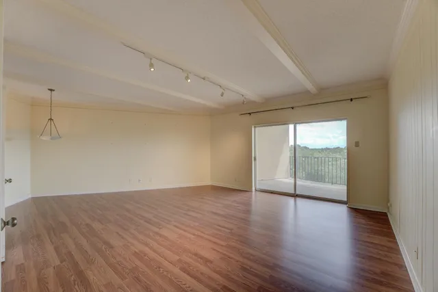a view of empty room with wooden floor and window