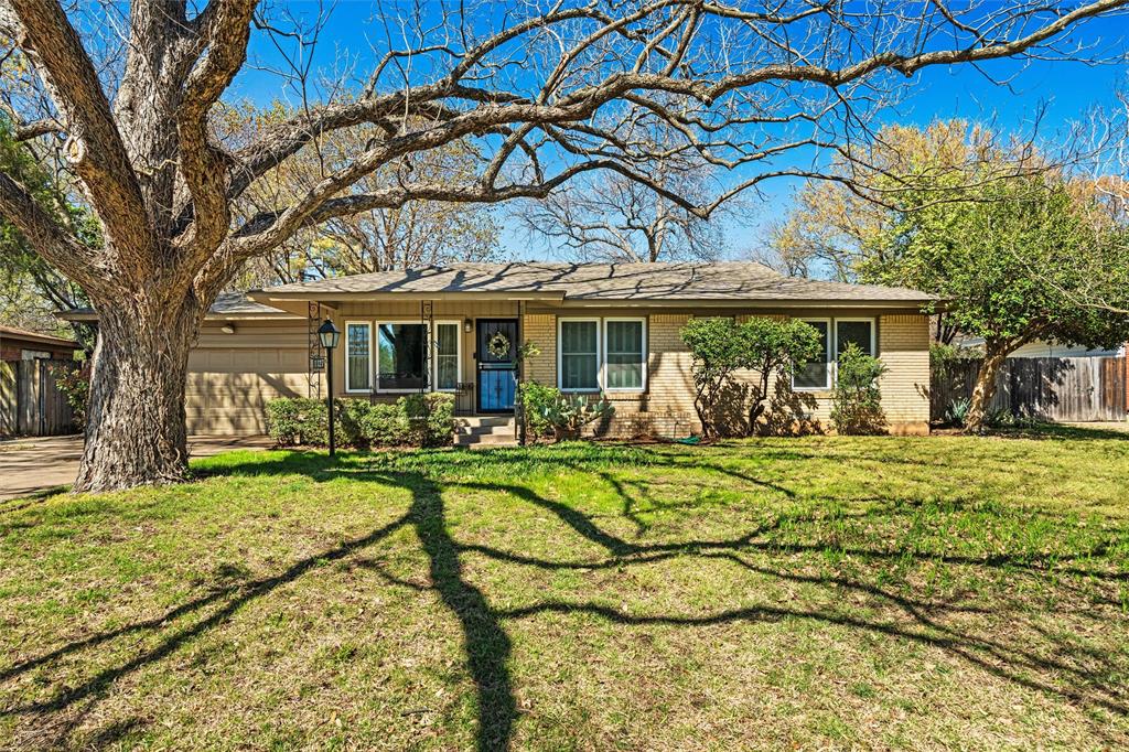 Single story home featuring brick siding, a garage, fence, and a front lawn