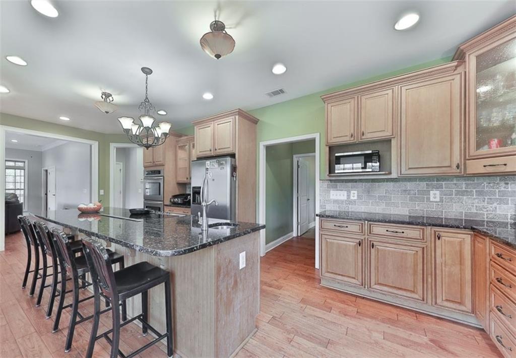 1523 Braswell Mountain Road Dallas, GA 30132 - Photo 12 of 34 a large kitchen with kitchen island granite countertop lots of white cabinets appliances and dining table