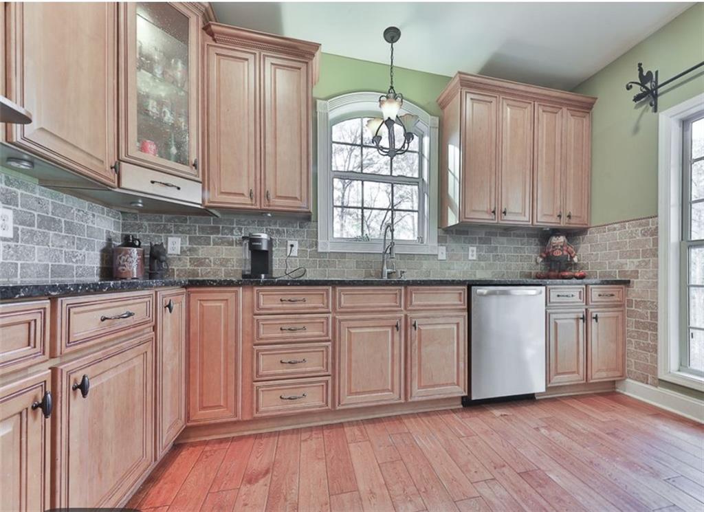 1523 Braswell Mountain Road Dallas, GA 30132 - Photo 10 of 34 a kitchen with stainless steel appliances granite countertop wooden cabinets a sink and dishwasher with wooden floor