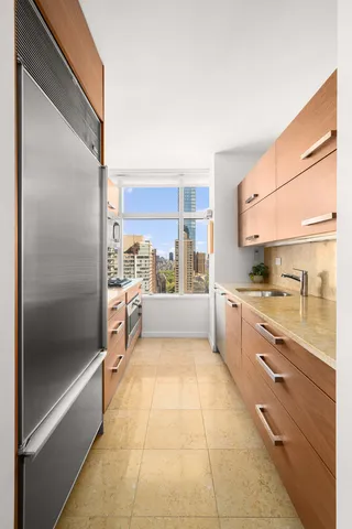 a large white kitchen with granite countertop a refrigerator and a sink