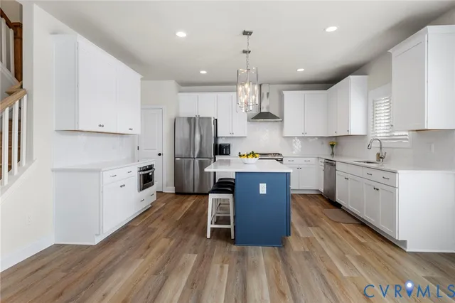 a kitchen with kitchen island a wooden floor stainless steel appliances and cabinets