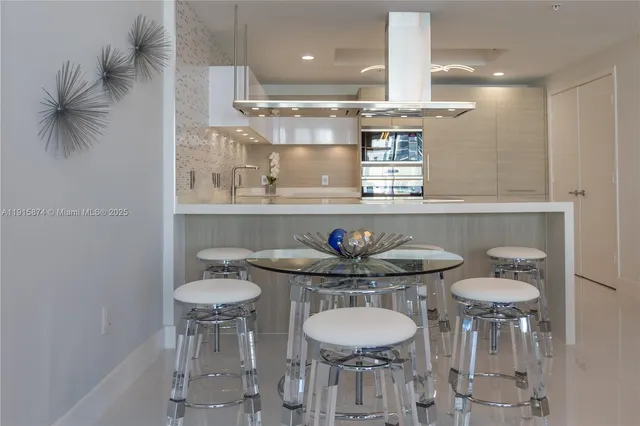 a kitchen with stainless steel appliances a table and chairs in it