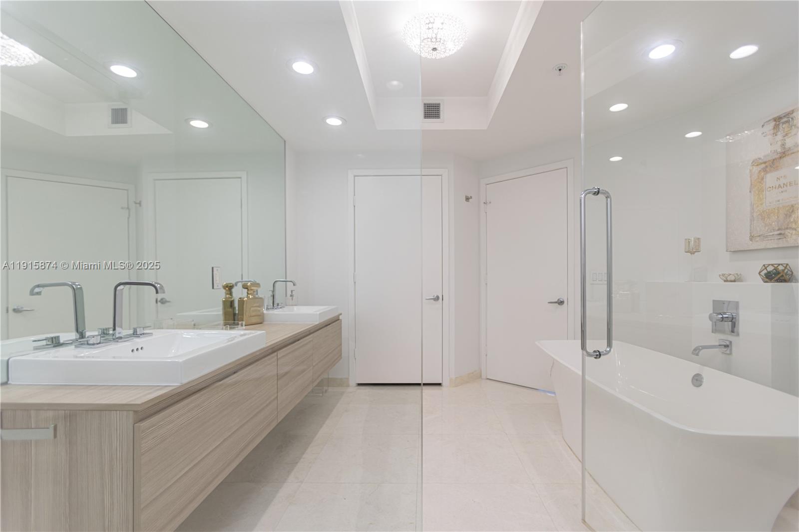 17111 Biscayne Boulevard, Unit 505 North Miami Beach, FL 33160 - Photo 5 of 29 a large white bathroom with a double vanity sink a mirror and a bathtub