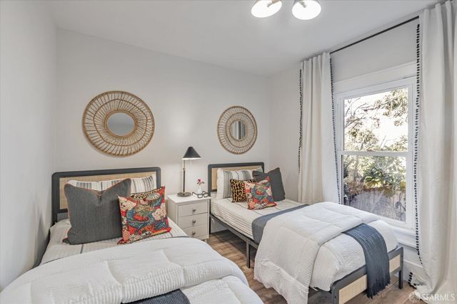a bedroom with bed and a lamp on dresser with a large window